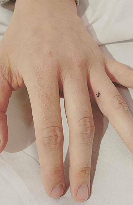 Tiny letter J tattoo located on the finger
